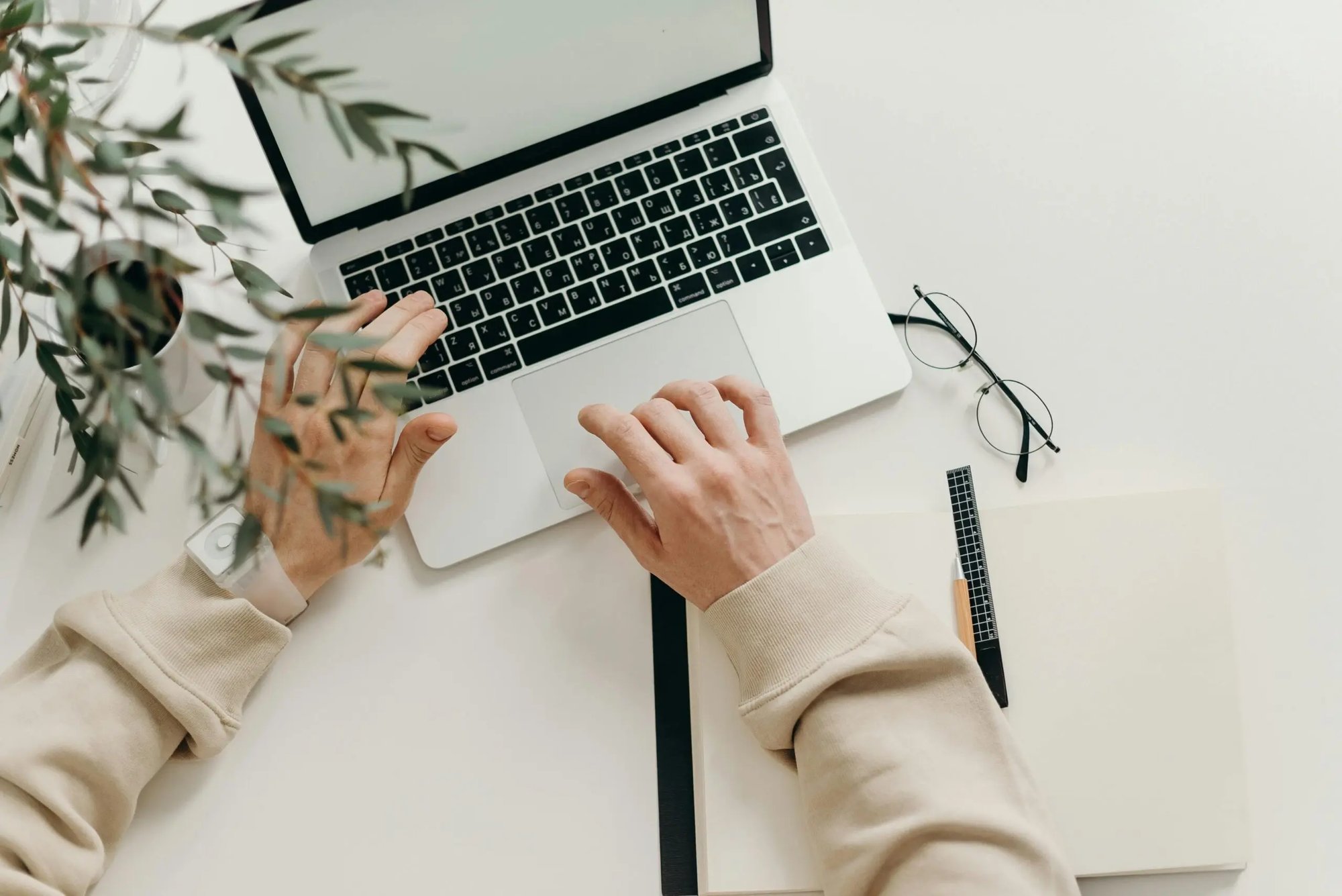 A photo of two hands typing on a laptop